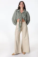 Pantalón jean color beige, de corte recto y tiro alto, con bolsillos delanteros y traseros, y detalle desflecado en los laterales.