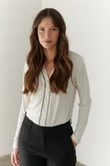 Remera blanca de mangas largas con escote en V y costuras decorativas en negro.