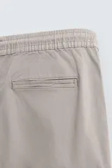 Pantalón cargo negro de corte slim fit, confeccionado en tejido de algodón con cintura elástica ajustable con cordón. Cuenta con bolsillos frontales, traseros y bolsillos tipo parche con solapa en los laterales.