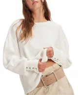 Buzo blanco de algodón con escote a la base, hombros caídos y mangas amplias con detalle de ojalillos y cordones en los puños.