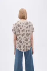 Remera blanca con estampado floral en color lila, de corte holgado y mangas cortas.