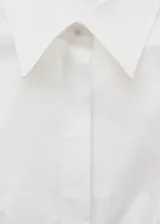 Camisa blanca de corte asimétrico con mangas largas y puños amplios.