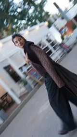 Abrigo largo marrón con mangas de cuero acolchado, cuello de piel sintética y cinturón de cuero.