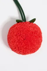 Charm para cartera color blanco con forma de fruta naranja con hojas verdes.