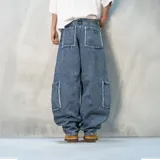 Pantalón jean azul de corte ancho, con bolsillos laterales y diseño de parches con bordes desflecados.