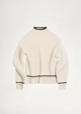 Sweater color crema de punto acanalado, con cuello alto y ribetes negros en cuello y ruedo.