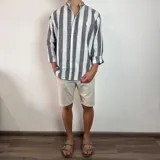 Camisa celeste y blanca a rayas verticales, de lino, con cuello mao y mangas largas con puños.