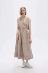 Vestido midi color beige de lino, sin mangas, con escote en V, bolsillos laterales y cordón ajustable en la cintura.