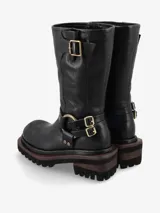 Bota de cuero negro de inspiración biker con caña media. Presenta un diseño robusto con correas ajustables, hebillas metálicas y una argolla decorativa con tachas en el tobillo. Posee suela track de goma para mayor tracción y estabilidad.