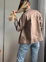Campera de corte clásico color marrón, con detalles desgastados y cuatro bolsillos frontales.