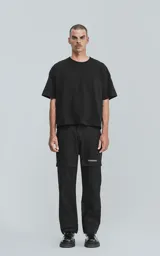 Pantalón de gabardina negro con corte recto, bolsillos laterales con solapa y detalles de texto estampado en blanco.
