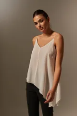 Blusa blanca de poliéster con breteles finos, escote en V, corte asimétrico y volados.