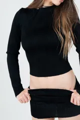 Camiseta negra de manga larga, cuello alto y corte crop. Tejido texturizado con líneas verticales.