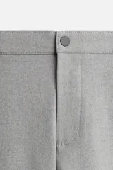 Pantalón negro de corte slim fit, confeccionado en tejido elástico. Cuenta con cintura elástica, bolsillos frontales y traseros de vivo. Cierre frontal con cremallera y botón.