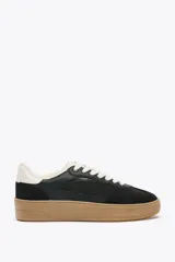 Zapatillas deportivas negras con detalles en cuero sintético y suela de goma color caramelo.