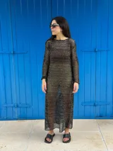 Vestido largo de tejido de punto abierto, color negro con hilos dorados brillantes. Diseño de manga larga y escote redondo.