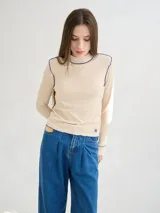 Polera negra de tela rib con cuello alto y mangas largas. Presenta pespuntes rojos en cuello, hombros y puños.