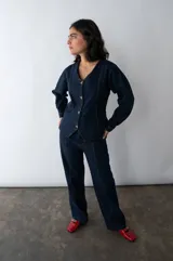Camisa entallada de denim azul oscuro con cuello en V y cierre frontal con botones. Confeccionada en algodón reciclado con espalda ajustable.
