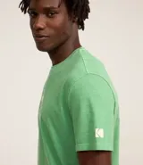 Remera verde con estampa de la marca Kodak y photoprint de playa paradisíaca.