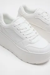 Zapatillas blancas con plataforma gruesa, cordones y puntera redonda.