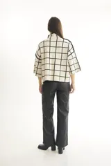 Sweater color crema con cuello alto y mangas cortas anchas, con diseño de cuadros negros.