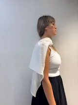 Poncho corto de gasa blanca, con escote amplio tipo barco y mangas amplias. Se lleva sobre otra prenda.