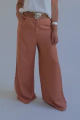 Pantalón de lino color terracota, de corte palazzo y cintura alta con cinturón de soga trenzada.