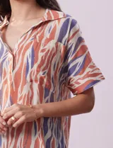 Blusa de gasa bambula estampada con cuello con solapa, escote en V y botón. Tiene un bolsillo aplicado en la parte delantera.