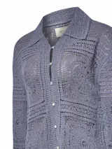 Sweater color crudo tejido a crochet con diseño de cuadrados y círculos, cuello camisero, mangas largas y cierre frontal con botones.