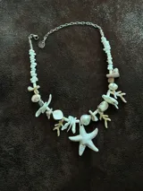 Collar corto con cuentas de nácar en diferentes formatos, perla natural XL y medallón de resina. Se cierra con cadena de acero quirúrgico y ganchito para regular el largo.