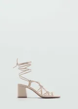 Sandalias color beige con tacón bloque y tiras finas que se atan alrededor del tobillo.