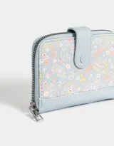 Billetera pequeña de cuerina color crema con estampado de flores pequeñas, cierre perimetral con cremallera y broche con botón a presión.