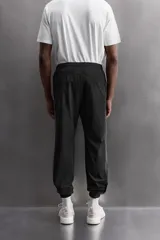 Pantalón relaxed fit confeccionado en tejido técnico ligero y elástico en todas direcciones. Cintura elástica ajustable con cordón interior, bolsillos delanteros y bajo acabado en elástico y ajustable con cremallera.