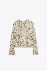 Blusa de viscosa con estampado de piel de serpiente en tonos beige y marrón. Tiene cuello redondo con lazo ajustable, mangas largas acampanadas con cordones en los puños y bajo recto.