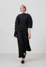 Pantalón palazzo negro con textura crinkle, cintura elástica, godets centrales y pierna ancha.