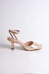 Sandalia de fiesta dorada con diseño elegante y minimalista. Presenta punta cuadrada, tira delantera ancha y pulsera al tobillo con hebilla regulable.