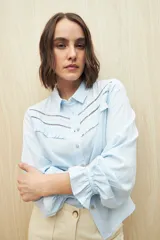 Camisa celeste de manga larga confeccionada en viscosa ligera, con detalles calados en la parte superior y pequeños volados.