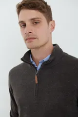 Sweater verde militar de tejido acrílico con textura tipo cashmere, cuello alto con medio cierre metálico y tirador de cuerina ecológica.