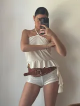 Short blanco de tiro alto con lentejuelas y cinturón marrón con tachas.