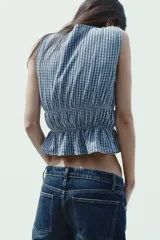 Top amarillo con estampado de cuadros vichy blancos, escote en pico, sin mangas, con detalle de elásticos en la cintura y cierre frontal con lazadas.