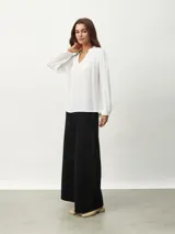 Blusa blanca de manga larga con escote en V y textura arrugada.