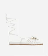 Sandalias planas blancas de cuero sintético, con tiras finas, puntera redonda, lazo para atar al tobillo y maxi flor aplicada en la capellada.