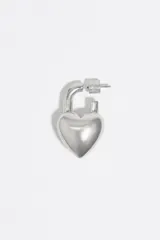 Caravanas de latón con acabado plateado en forma de corazón con diseño de candado. Cuentan con cierre a presión y logo grabado en el frente.