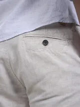 Bermuda color beige claro, de corte casual y largo por encima de la rodilla, con bolsillos laterales.