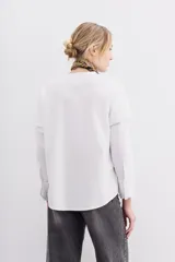 Remera blanca de algodón con mangas largas y calce recto. Diseño de doble capa, con remera de mangas rebatidas y camisa clásica debajo.
