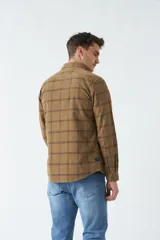 Camisa de pana a cuadros en tonos oscuros, con manga larga y bolsillos con botones.