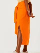 Pollera midi color naranja con lazo en la cintura y abertura lateral.