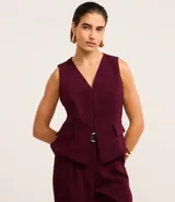 Chaleco color borgoña con escote en pico y cierre sencillo. La prenda tiene una solapa delantera que da la apariencia de bolsillos.