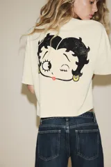 Camiseta color crema de cuello redondo y manga corta, con estampado frontal de Betty Boop y texto en rojo.