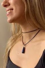 Gargantilla con tira de cuero negro y dije de piedra natural azul en forma de gota.